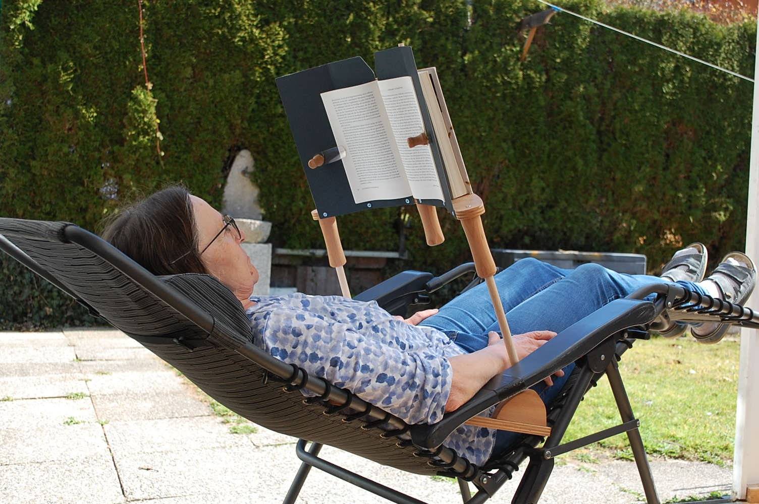 Frau liest entspannt im Liegen auf einem Gartenstuhl mit dem BookBock Lesegestell – freihändiges Lesen im Freien